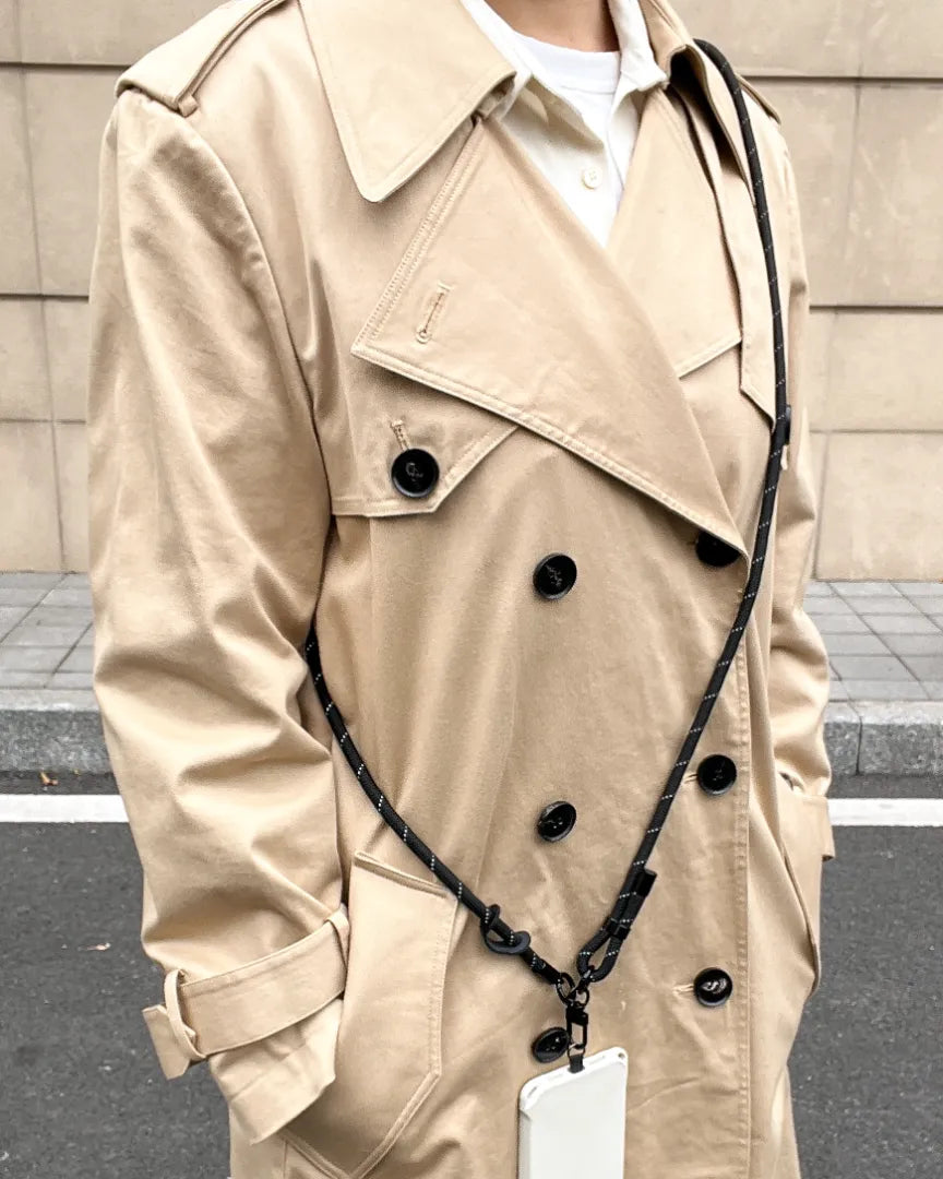 Black phone strap worn with minimalist outfit, emphasizing neutral style and hands free phone carrying#color_black