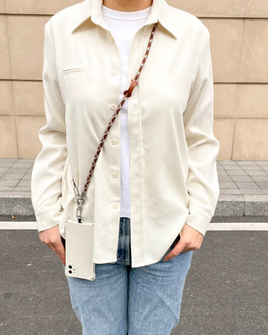 Fashionable brown and white braided phone lanyard worn in a crossbody style over a white shirt#color_brown