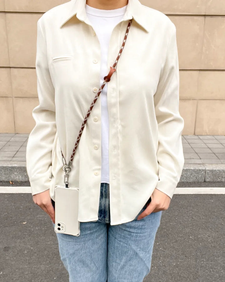 Fashionable brown and white braided phone lanyard worn in a crossbody style over a white shirt#color_brown