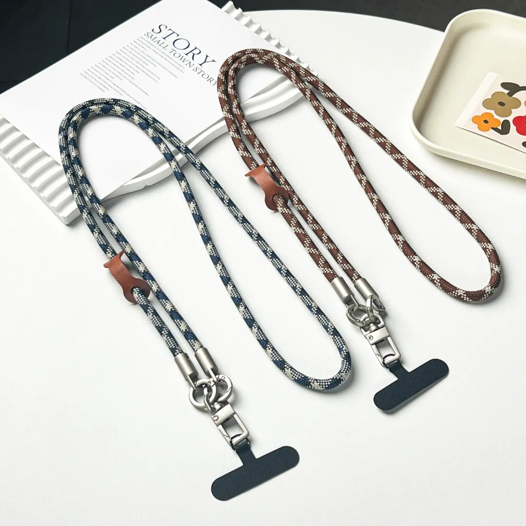 Brown and white patterned crossbody phone lanyard strap securely attached to a mobile case#color_brown