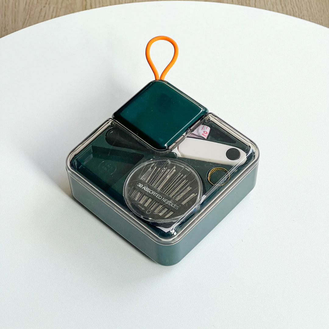 Close-up of a dark green metal sewing tin with organized thread spools, perfect gift for DIY sewing beginners.