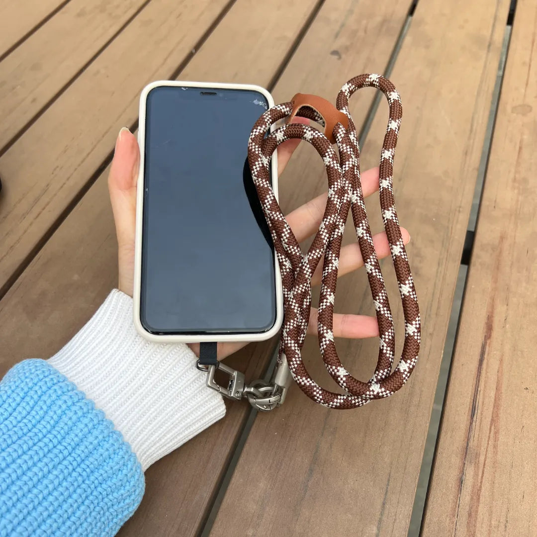 Close up of a person holding a smartphone with a brown and white braided phone lanyard strap#color_brown