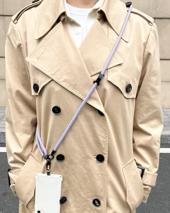 Lavender phone strap worn with layered outfit, adding subtle color accent while keeping the phone accessible#color_purple