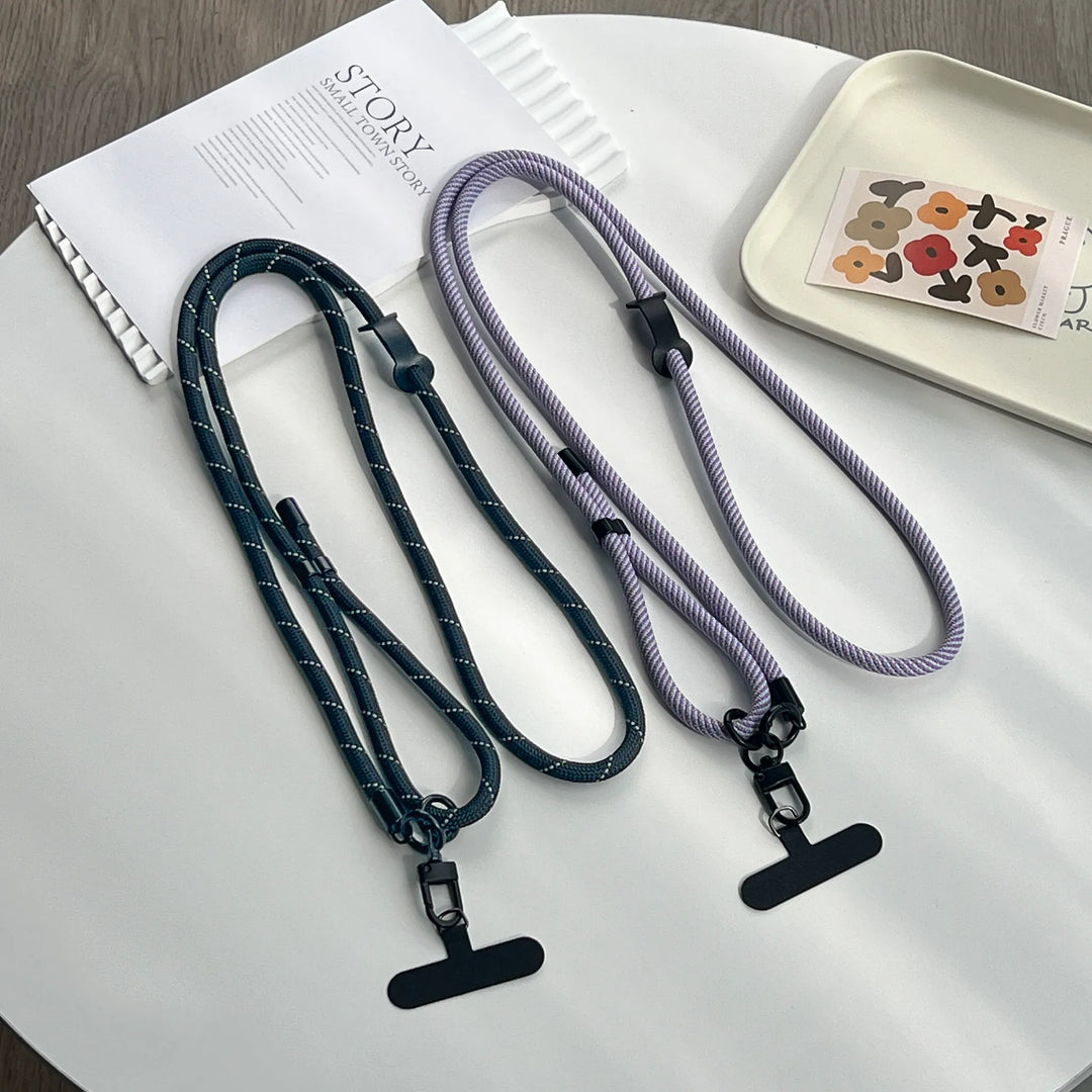 Two lanyards, one black and one purple, on a white surface with a magazine and decorative tray.#color_purple