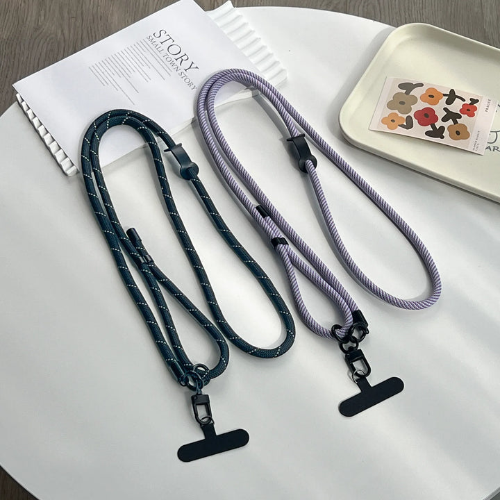 Two lanyards, one black and one purple, on a white surface with a magazine and decorative tray.#color_purple