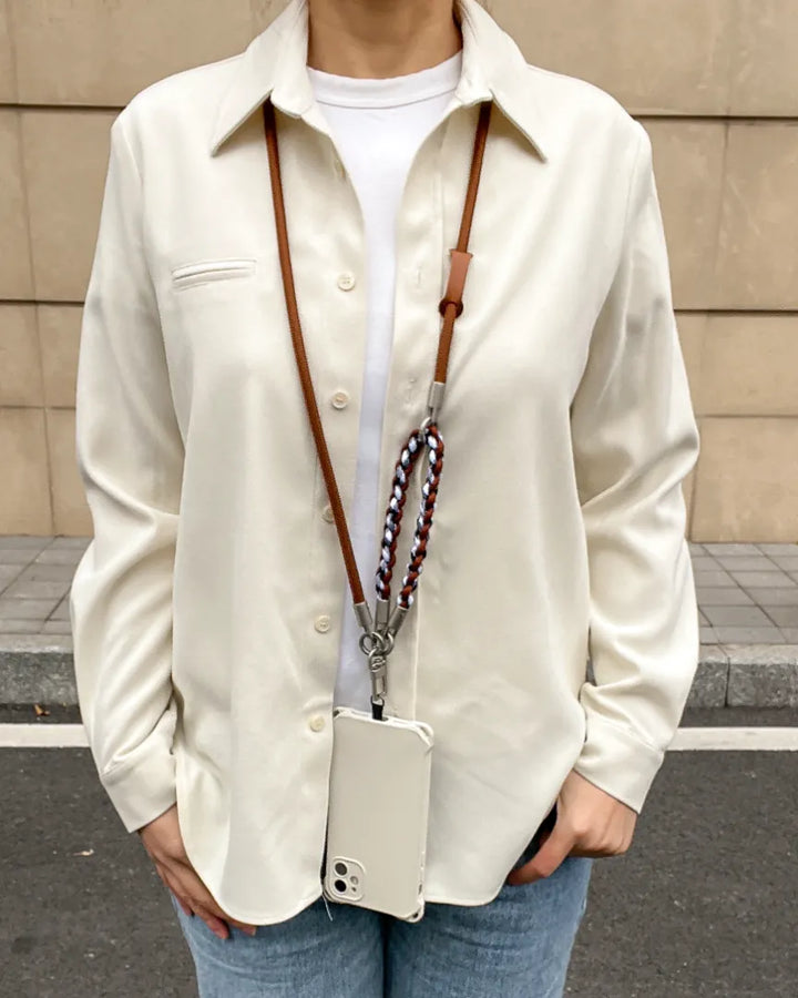Elegant long phone lanyard in brown leather worn as a functional crossbody fashion accessory#color_brown