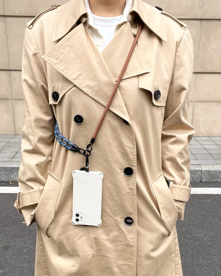 Fashionable woman wearing a navy blue crossbody phone strap with a classic beige outfit#color_brown