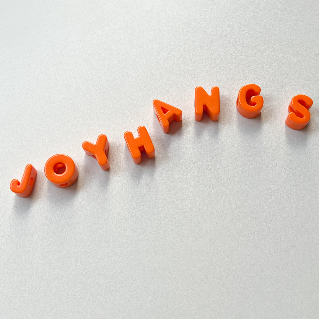 Individual orange alphabet letter beads for personalized jewelry making, easy to string for names and custom messages.