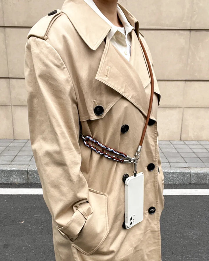Outdoor model shot showing a brown phone crossbody strap paired with stylish beige outerwear#color_brown