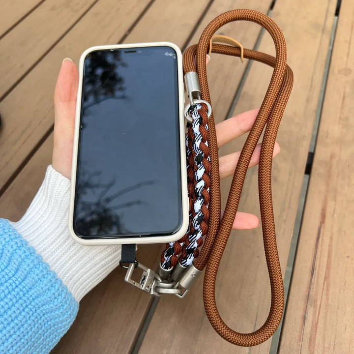 Close up of a person holding a smartphone with a brown braided leather phone wrist strap#color_brown