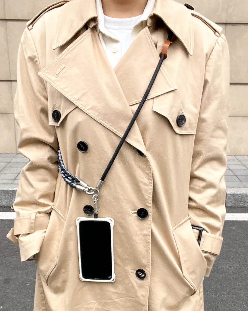 Rugged phone strap styled with trench coat outfit, combining functional design with practical everyday wear#color_black