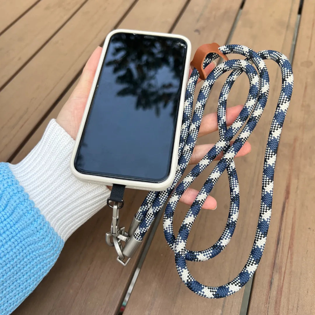 Close up of a smartphone with a grey and blue patterned leather wrist strap in hand#color_blue