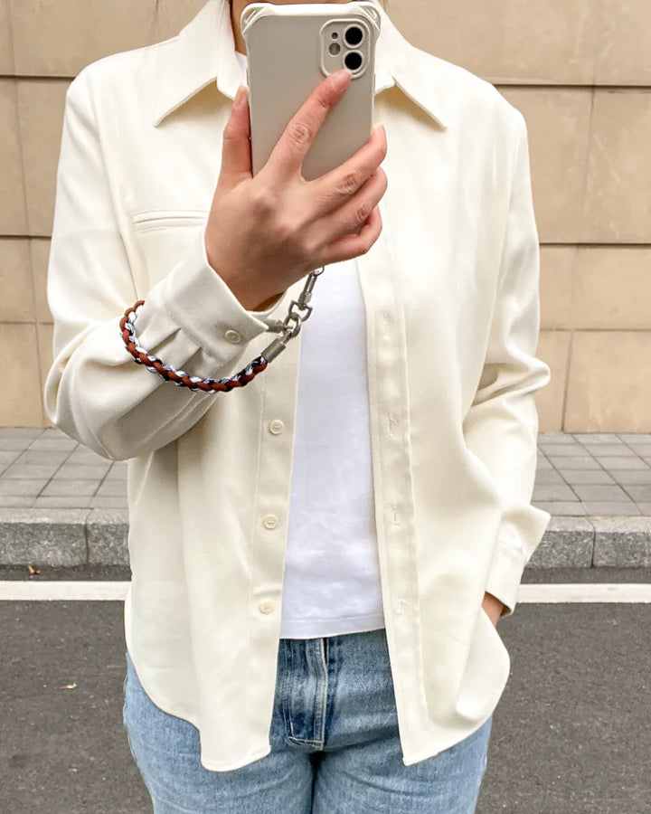 Close up of a woman using a brown leather weave phone strap for a hands-free lifestyle#color_brown